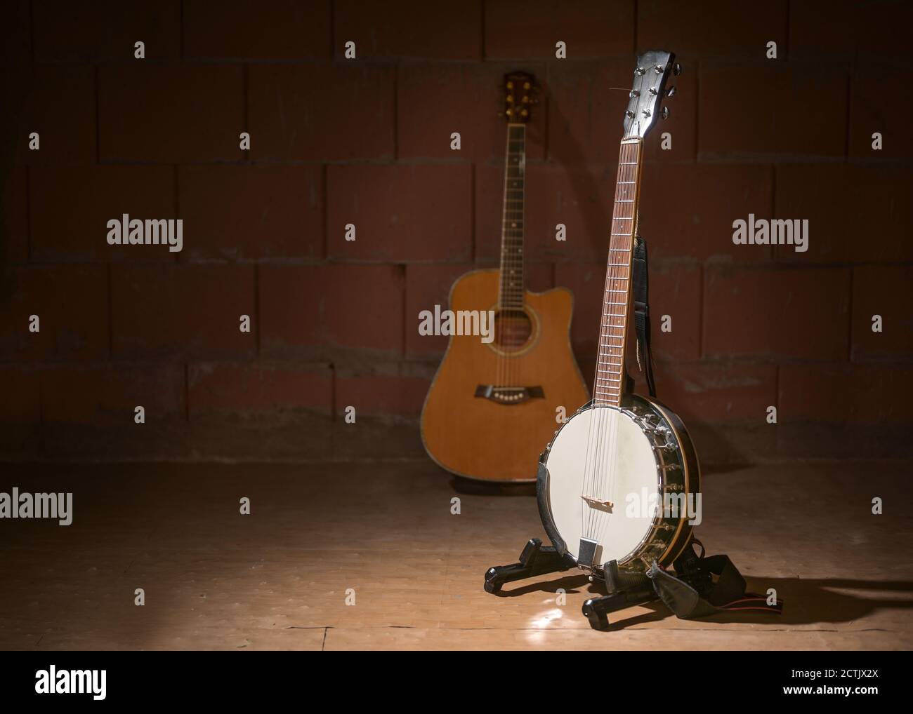 Banjo und eine verschwommene Gitarre im Hintergrund vor einer dunklen Ziegelwand in der Garage einer Musikband, Kopierraum, ausgewählter Fokus, enge Schärfentiefe Stockfoto