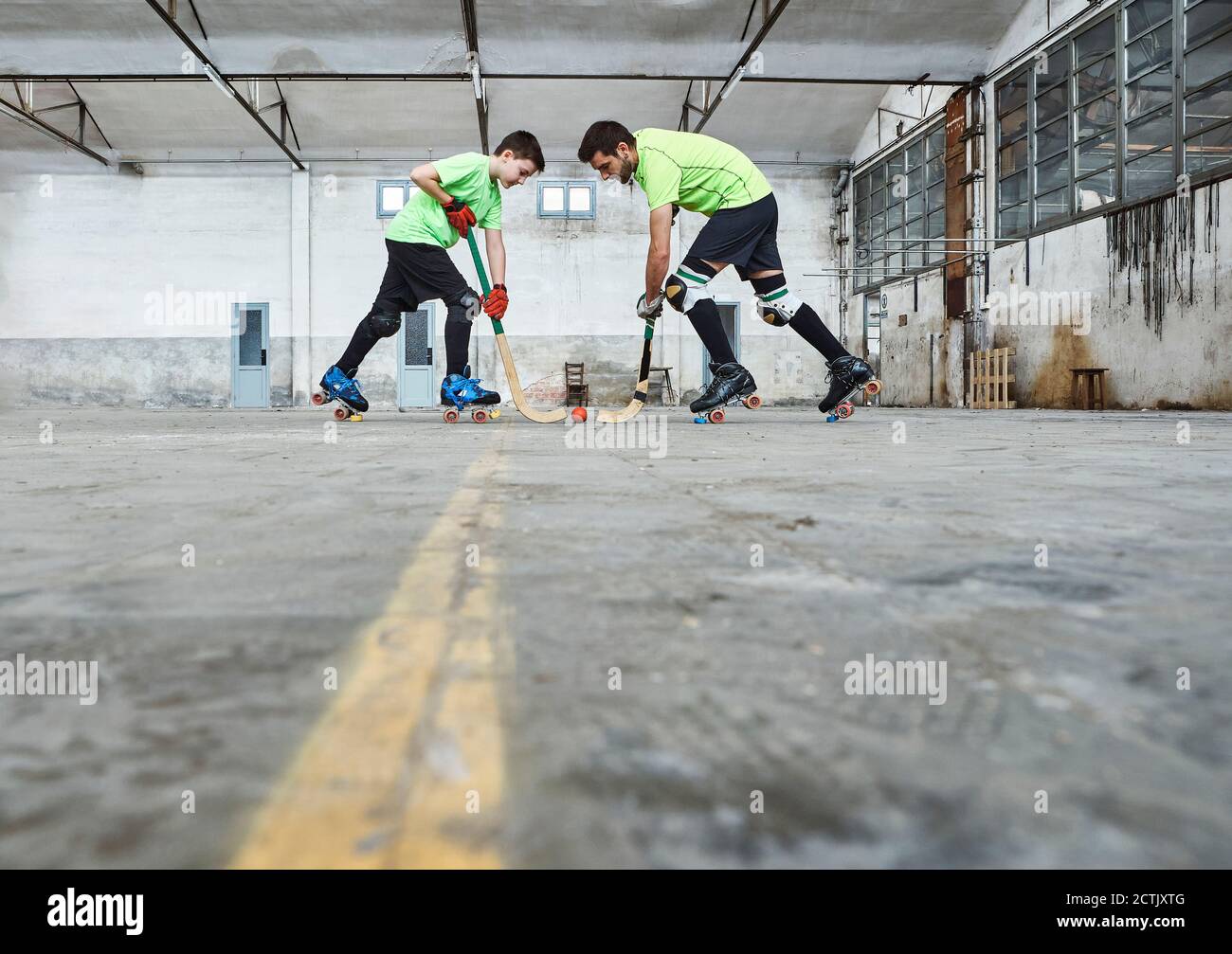 Oberflächennahe Ansicht von Vater und Sohn im Gesicht weg Während des Rollhockeyspiels auf dem Platz Stockfoto