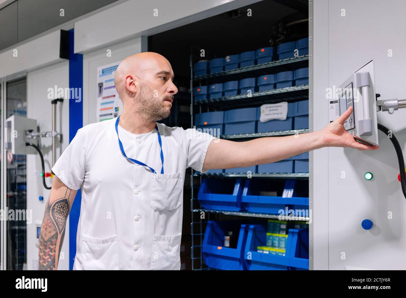 Kahlköpfiger männlicher Apotheker, der Computer benutzt, während er im Lagerraum steht Im Krankenhaus Stockfoto