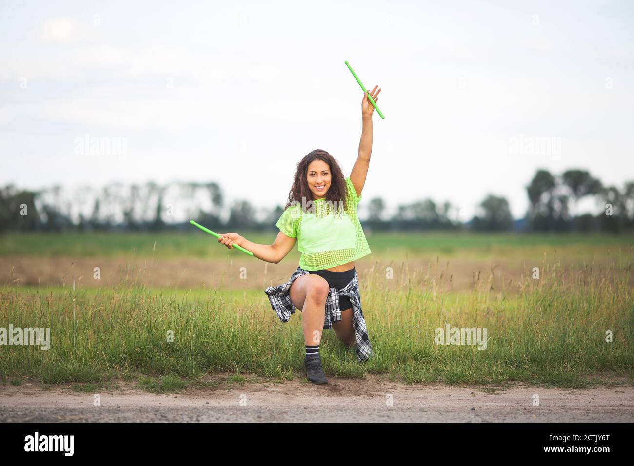 Fröhliche Frau tanzen mit Drumsticks auf dem Feld Stockfoto