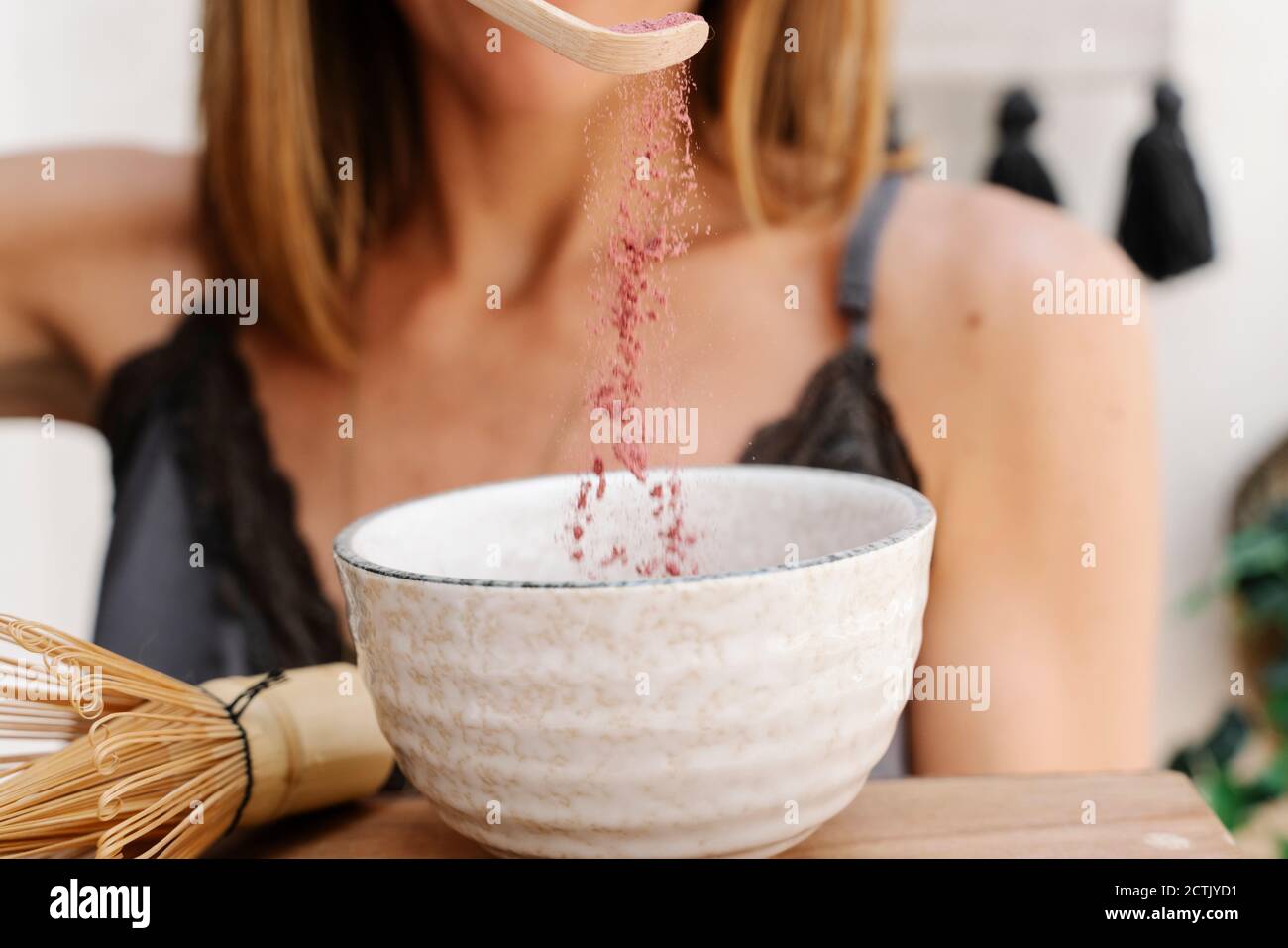 Frau, die Zutaten in einer Schüssel mischt, während sie Matcha Tee macht Stockfoto