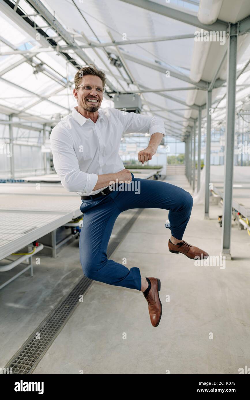 Fröhlicher Geschäftsmann springen im Gewächshaus Stockfoto