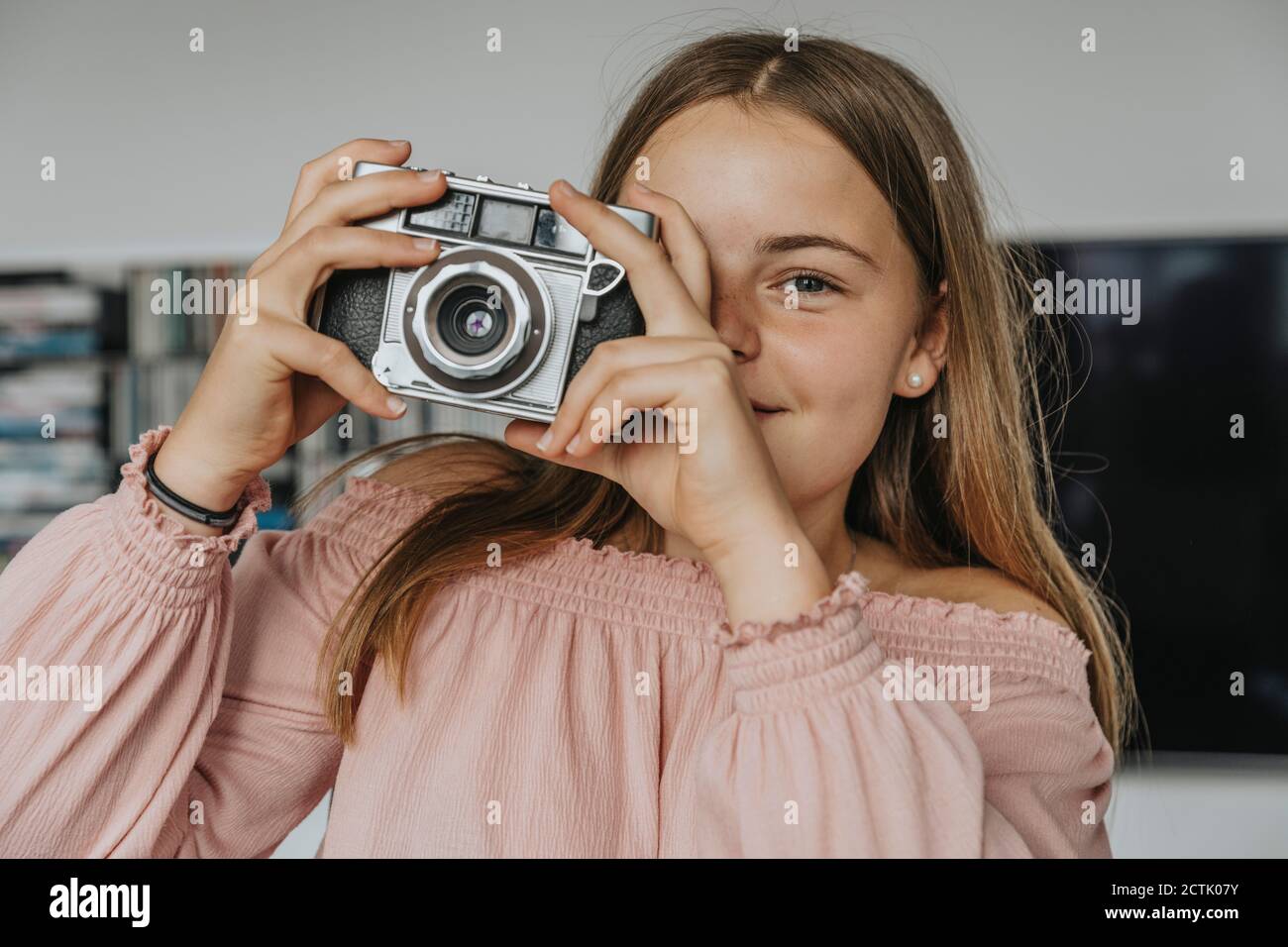 Nahaufnahme eines Mädchens, das mit einer alten Kamera zu Hause fotografiert Stockfoto