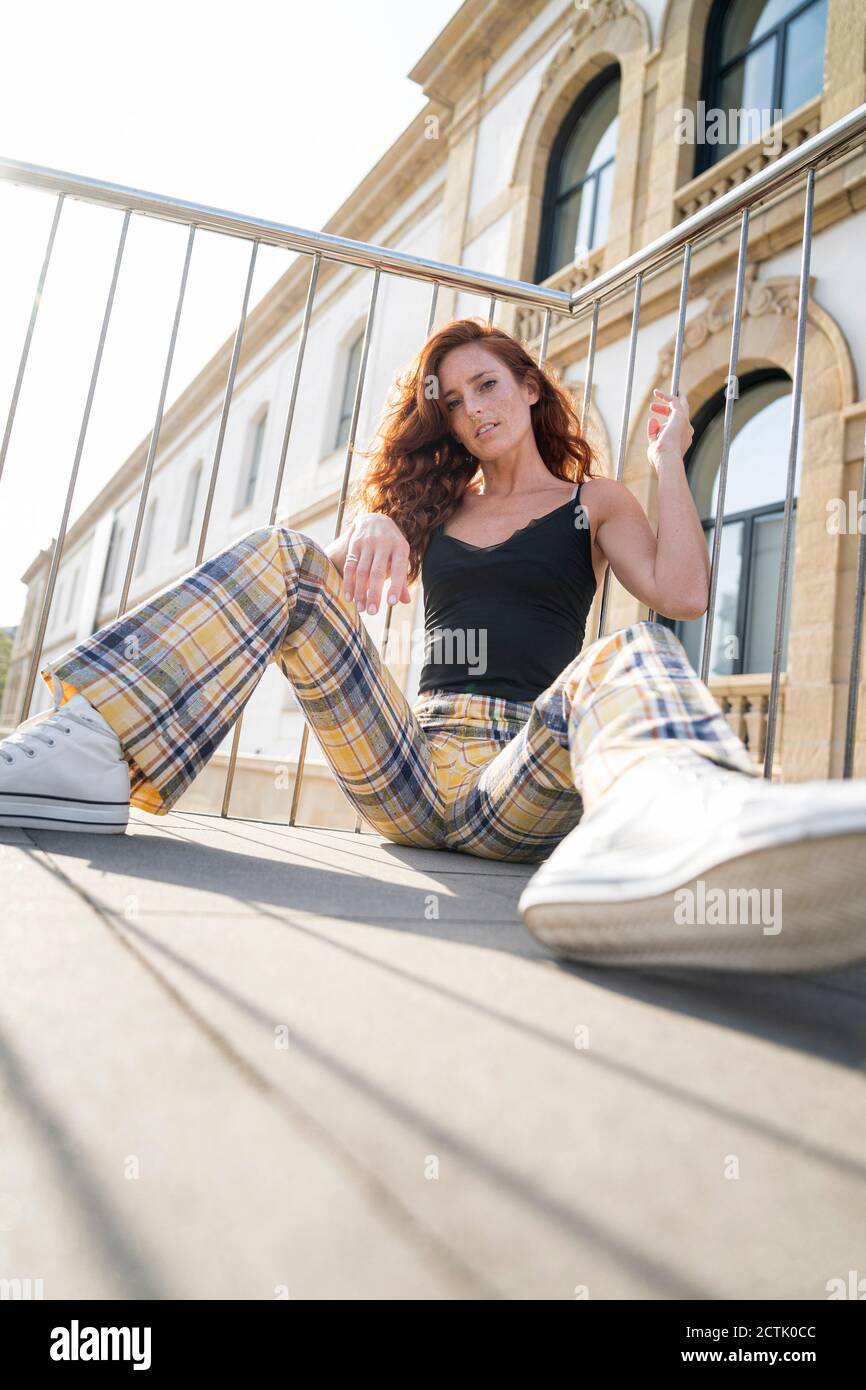 Oberflächenebenansicht einer schönen Frau, die auf einem Steg sitzt Stadt an sonnigen Tagen Stockfoto
