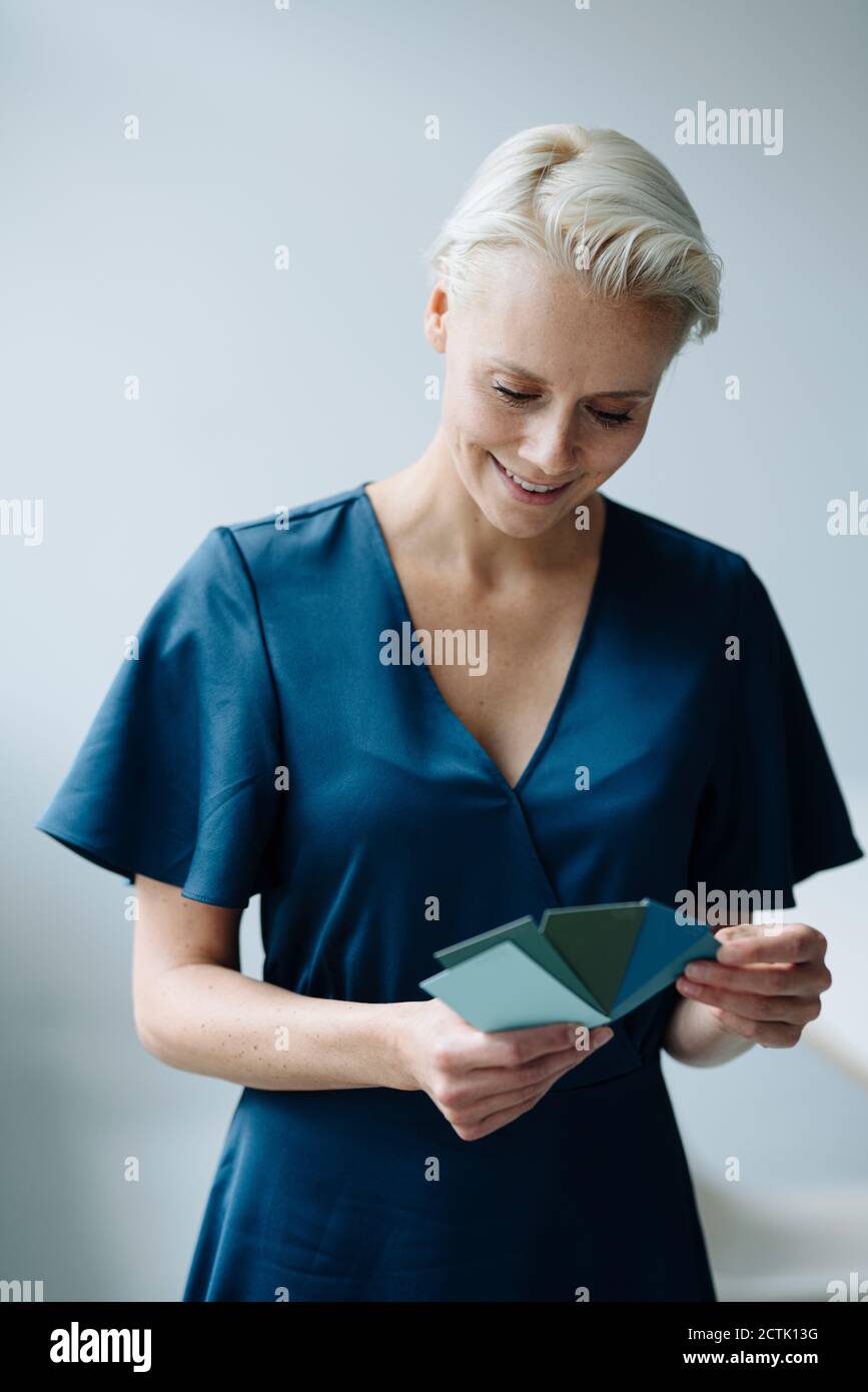 Geschäftsfrau wählt Farbmuster, während sie im Büro gegen die Wand steht Stockfoto