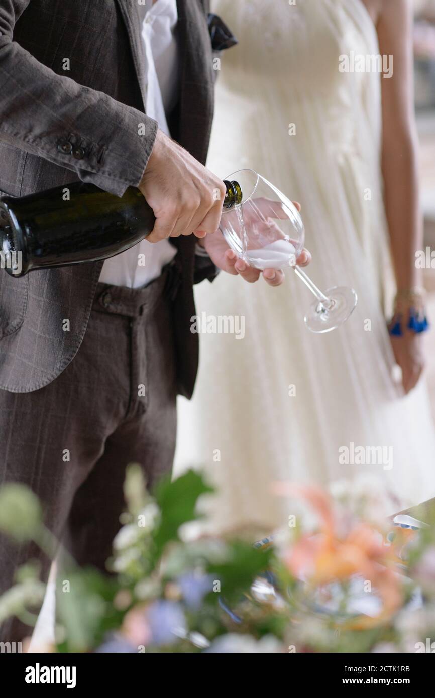 Bräutigam Hand Gießen Champagner in Flöte, während Sie bei der Braut stehen Stockfoto
