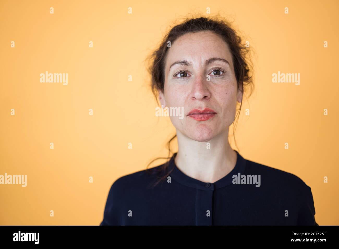 Nahaufnahme einer Unternehmerin gegen eine orangefarbene Wand Stockfoto