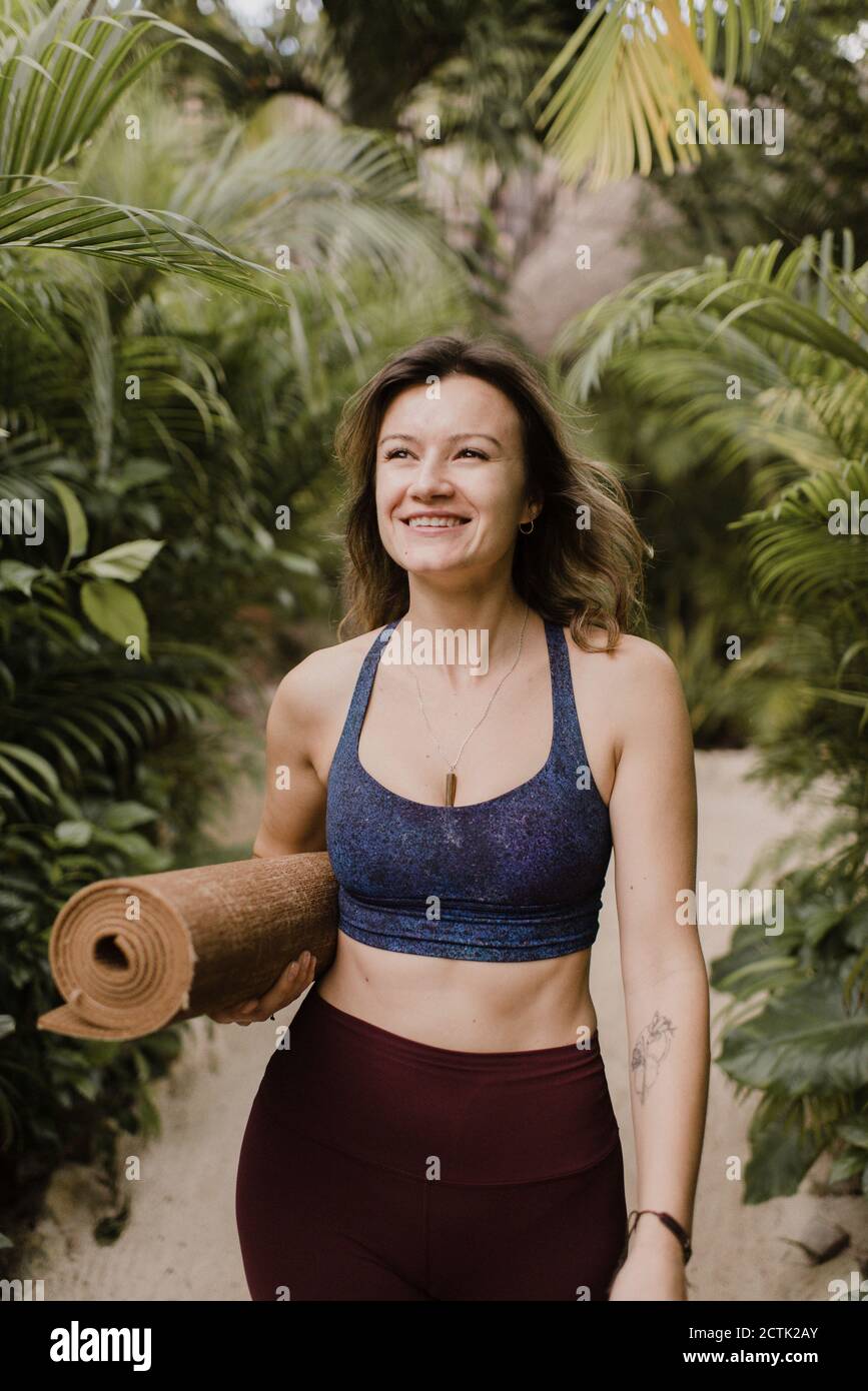 Lächelnde Frau mit Yogamatte zu Fuß Stockfoto