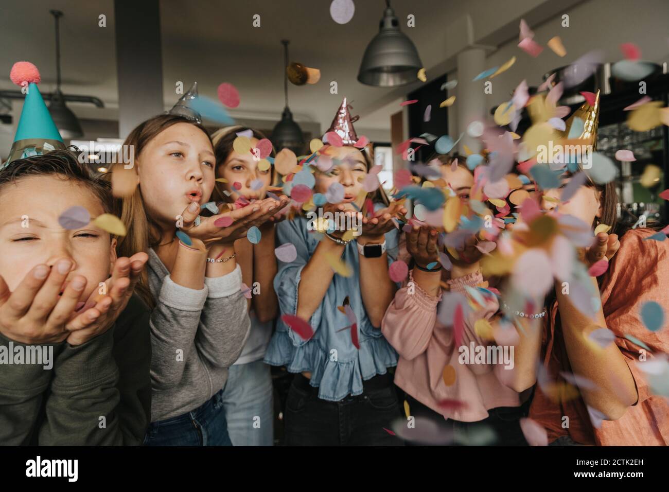 Spielerische Freunde blasen Konfetti während genießen Geburtstagsfeier zu Hause Stockfoto