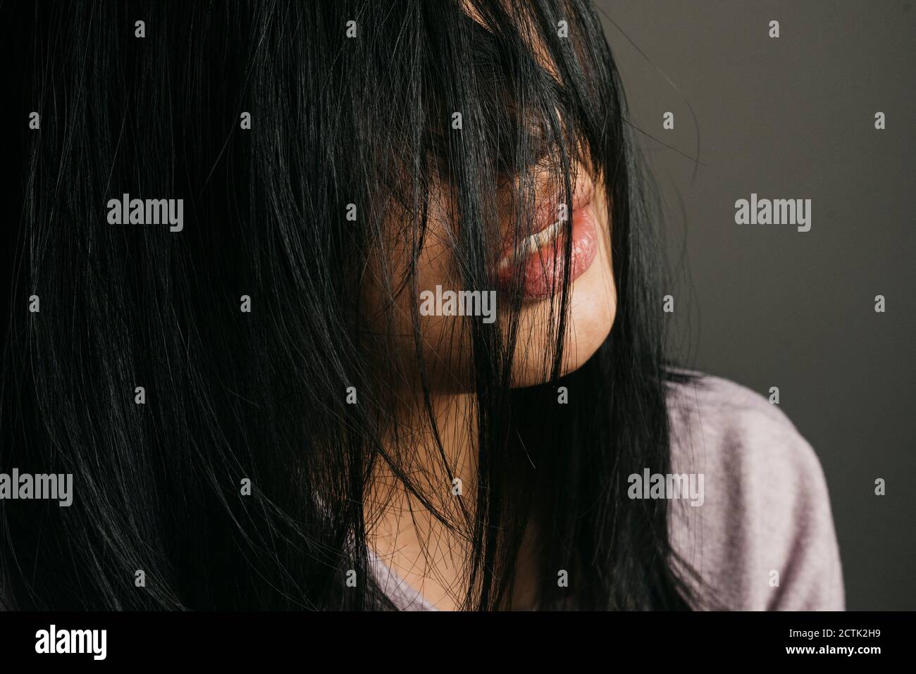Nahaufnahme einer Frau mit unordentlichen schwarzen Haaren an der Wand Stockfoto
