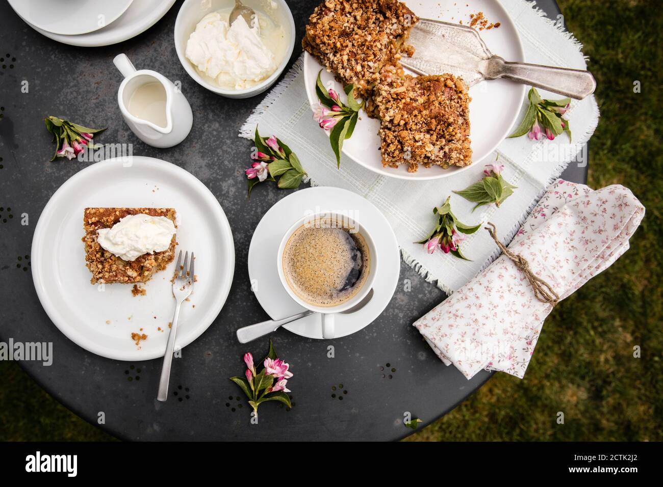 Tasse Kaffee und hausgemachter Rhabarberkuchen auf Gartenkaffee Tabelle Stockfoto