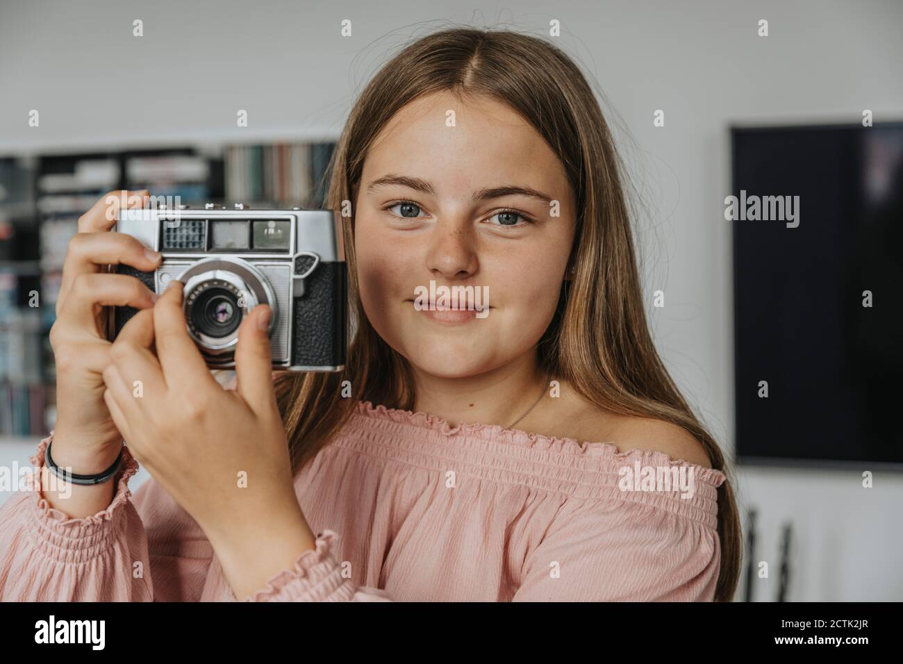Nahaufnahme eines Mädchens, das zu Hause eine alte Kamera hält Stockfoto