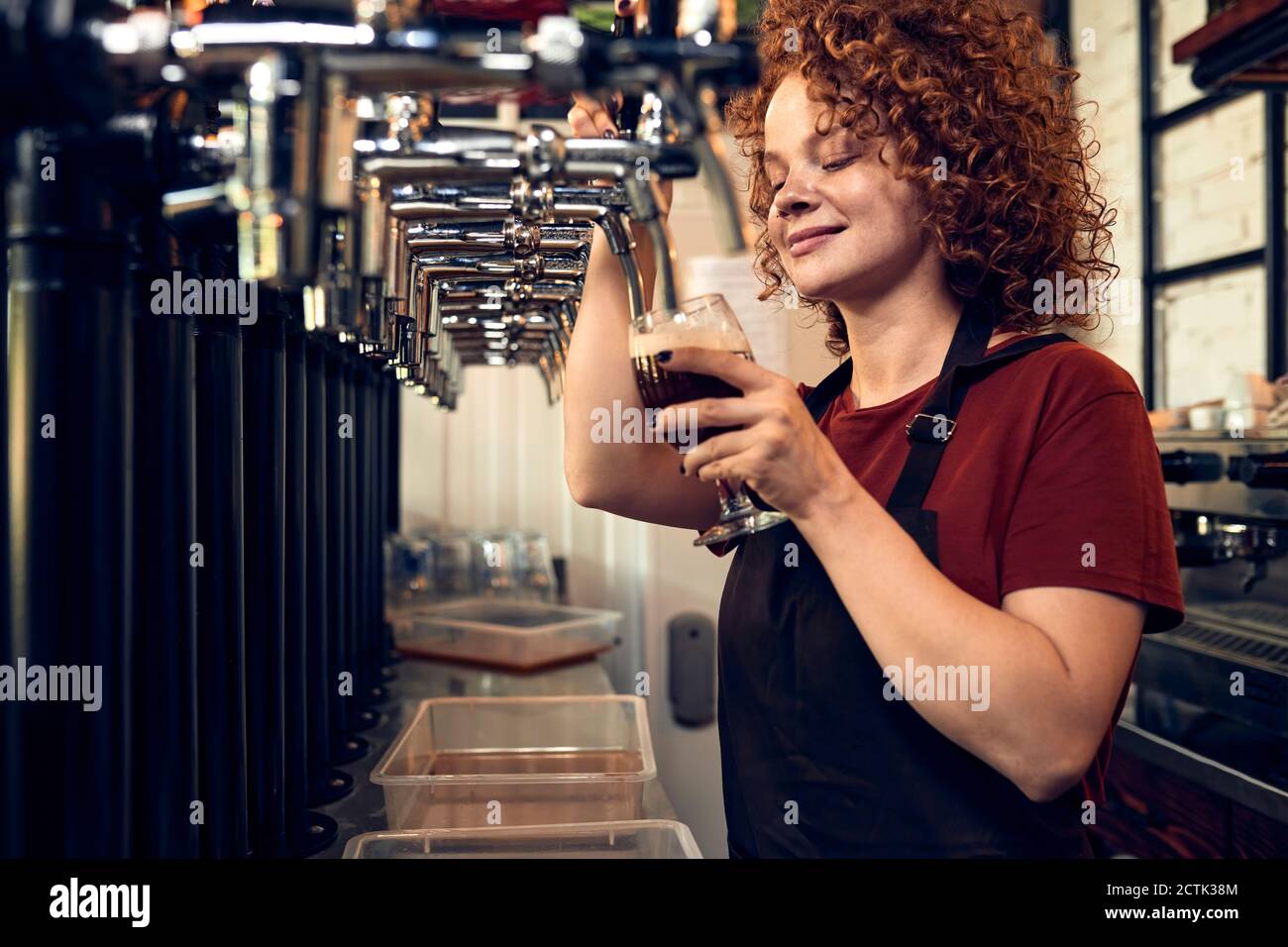 Die Barkeeperin klopft Bier in einem Pub Stockfoto