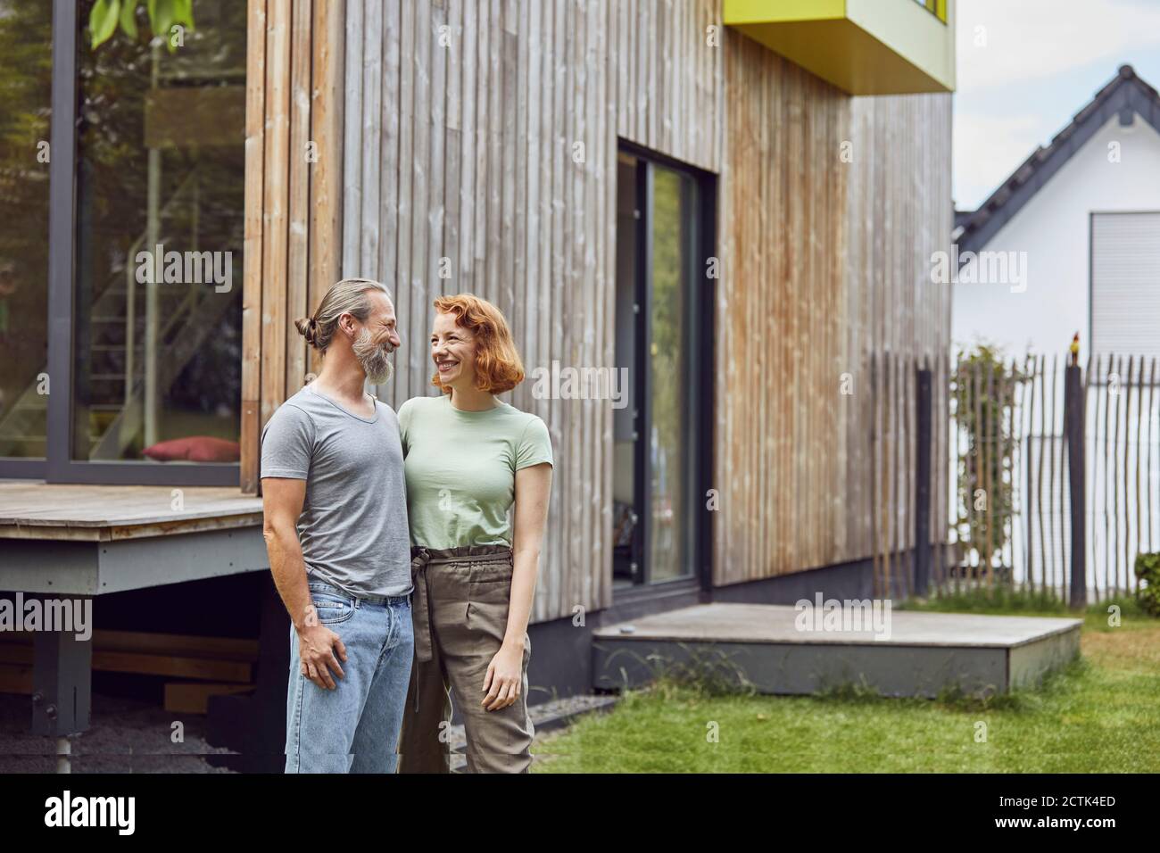 Romantisches Paar, das sich ansieht, während es draußen winzig steht Haus im Hof Stockfoto