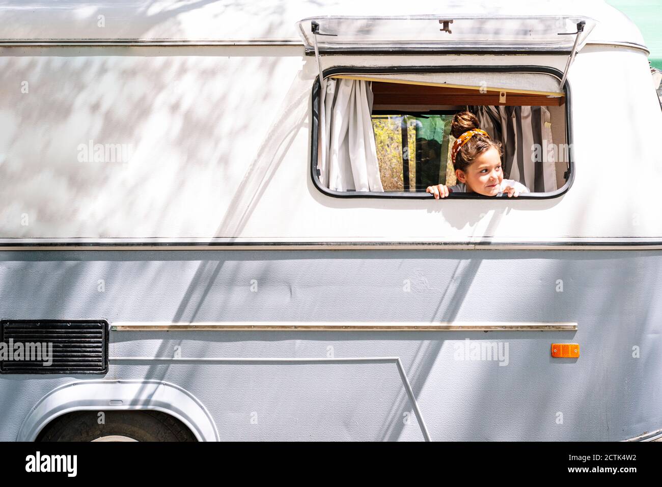 Mädchen, die durch das Fenster schaut, während sie im Wohnheim sitzt Stockfoto