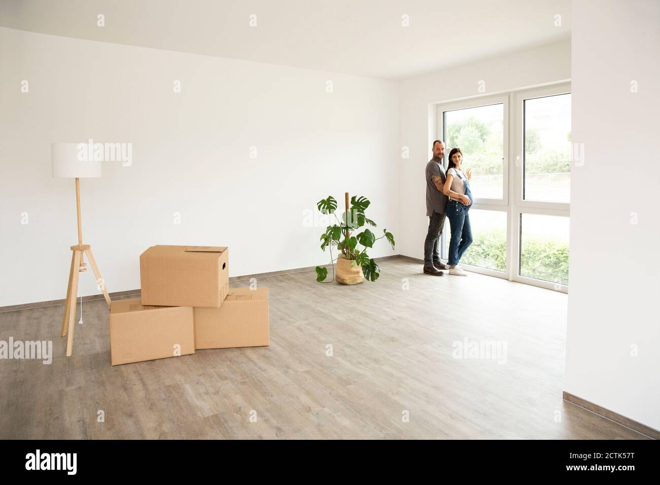 Mann und Frau stehen am Fenster in einem neuen unmöblierten Haus Stockfoto