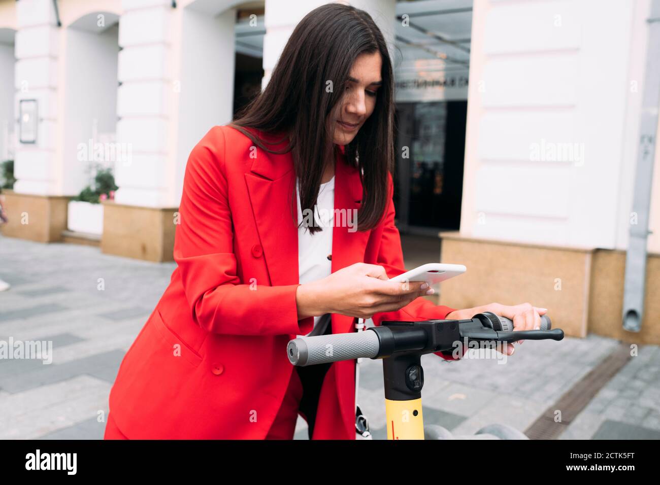 Schöne Geschäftsfrau Scannen QR-Code auf Elektro-Push-Roller Stockfoto