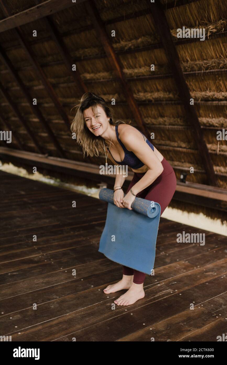 Lachende Frau rollt Yogamatte auf Stockfoto