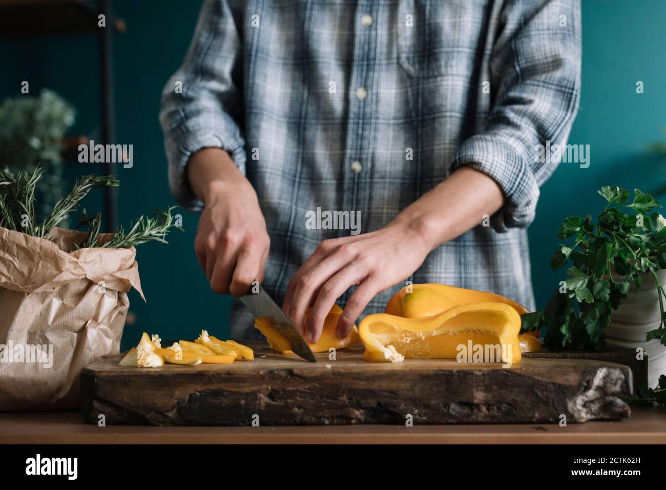 Hände von Mann schneiden gelben Paprika an Bord in Küche Stockfoto