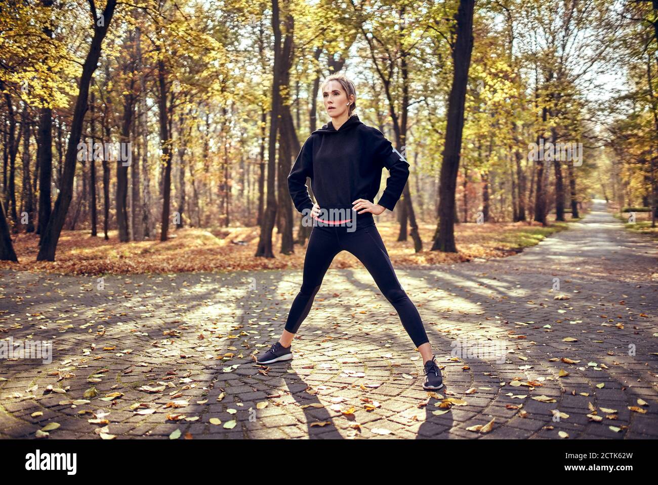 Junge Joggingin mit offenen Beinen im Herbstwald Stockfoto