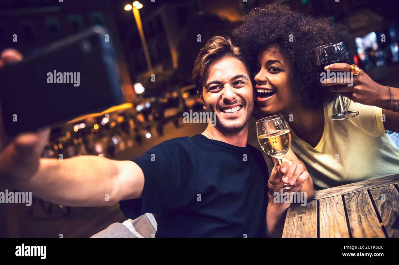 Fröhliches Paar hält Weingläser, die Selfie am Date Night nehmen Stockfoto