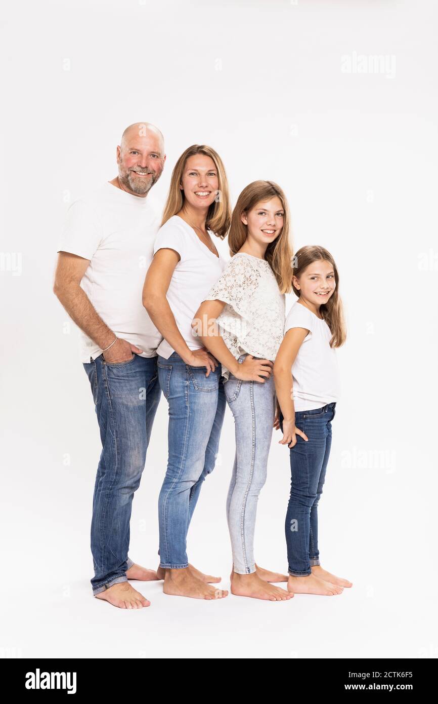 Lächelnde Familie mit Händen auf Hüften, die vor weißem Hintergrund stehen Stockfoto