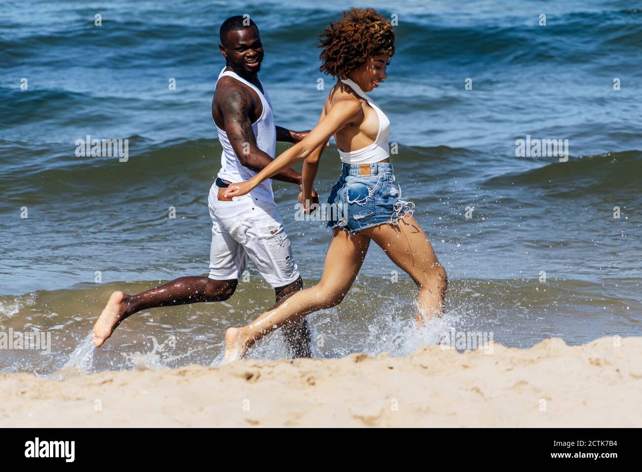 Sorgloses junges Paar, das an sonnigen Tagen im Meer läuft Stockfoto