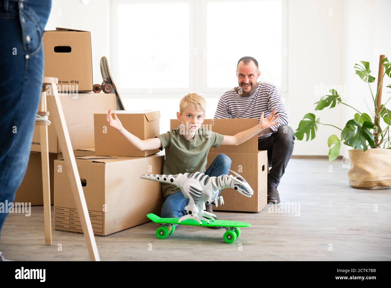 Mann Auspacken Boxen während Sohn spielt mit Spielzeug in neu Zu Hause Stockfoto
