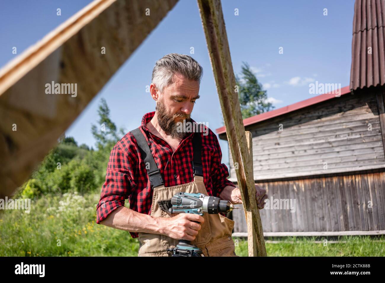 Zimmermann Bohren mit Elektrowerkzeug während der Herstellung Spielhaus Stockfoto