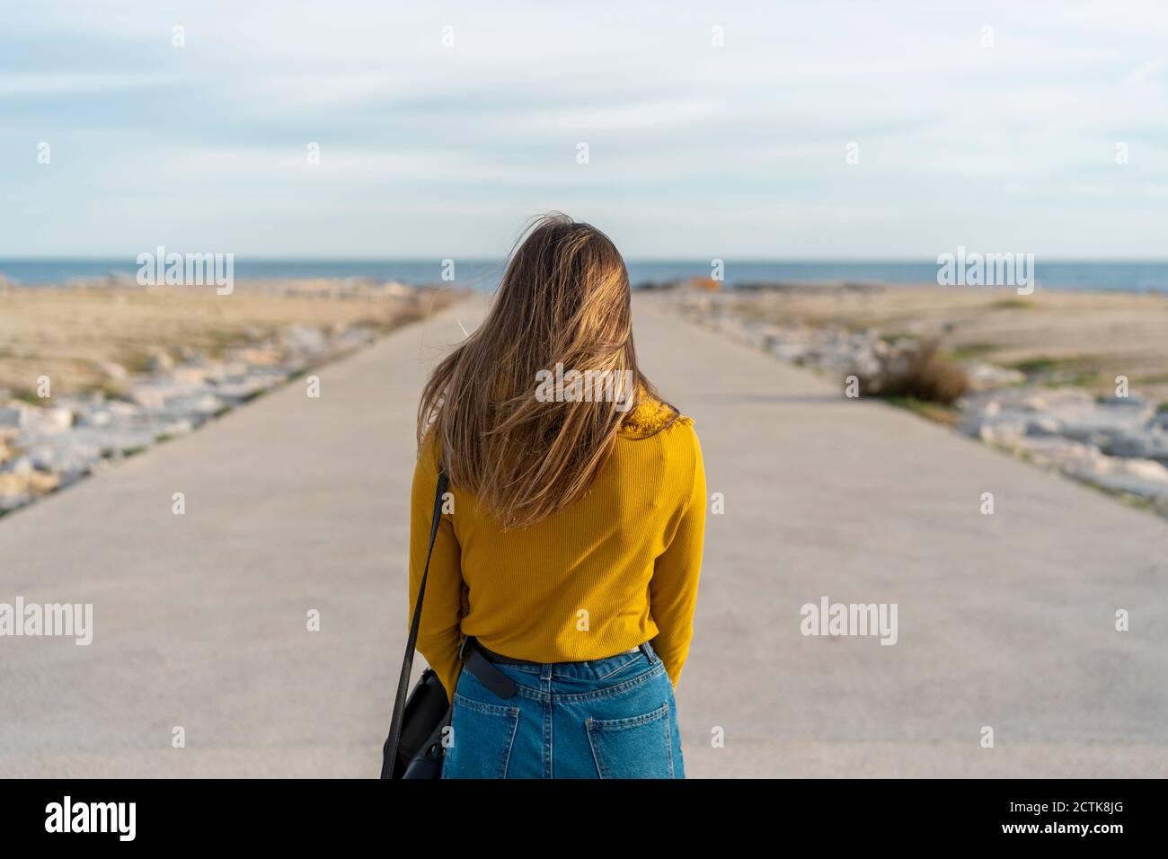 Frau mit Tasche, die auf dem Weg zum Meer steht Stockfoto