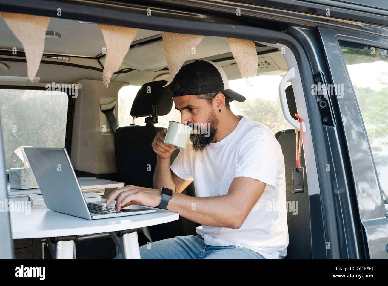 Reifer Mann mit Laptop, während schlürfen Kaffee in van Stockfoto
