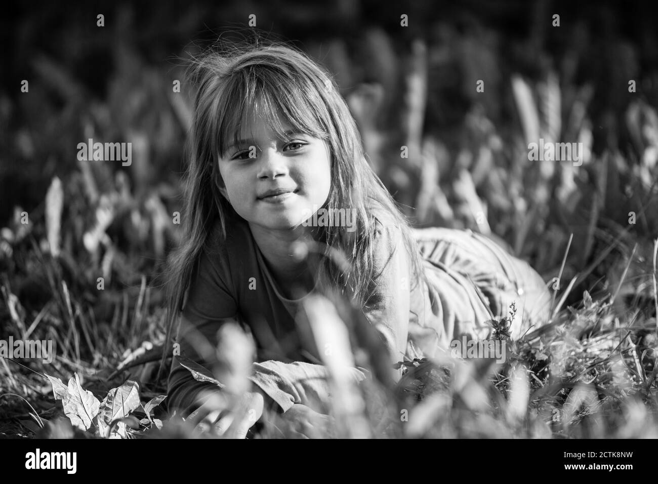 Kleines Mädchen liegt im Gras. Schwarzweiß-Fotografie. Stockfoto