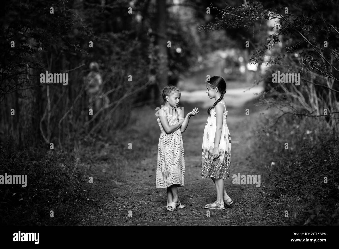 Kleine Freunde unterhalten sich aufgeregt im Park stehend. Schwarzweiß-Fotografie. Stockfoto
