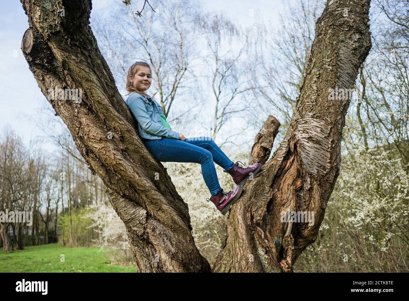 Lächelndes Mädchen balanciert über Baumstamm im Park Stockfoto