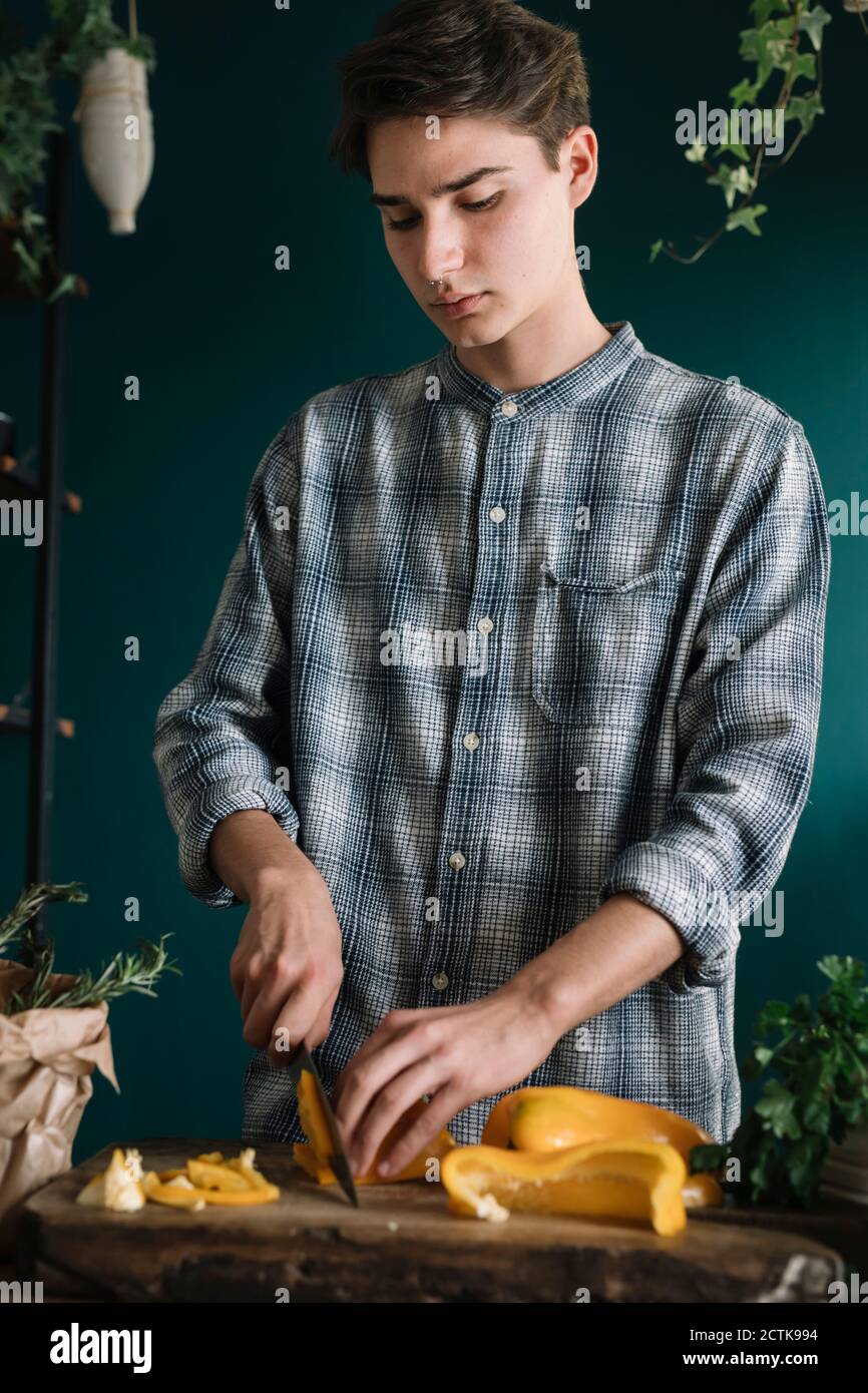 Hübscher Mann, der an Bord Paprika schneidet, während er steht Zu Hause Stockfoto