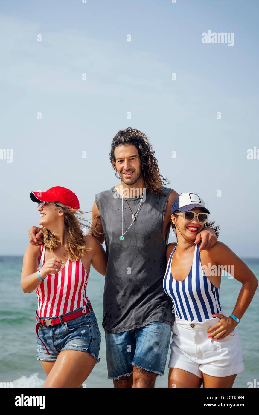 Lächelnder Mann mit Freundinnen am Strand während des Urlaubs Stockfoto