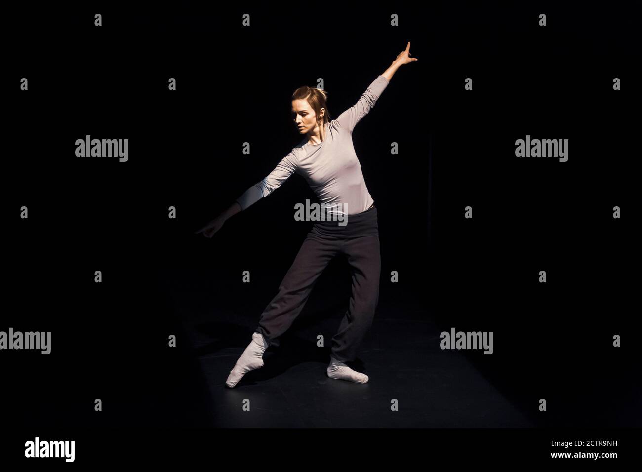 Balletttänzerin probt auf schwarzer Bühne Stockfoto