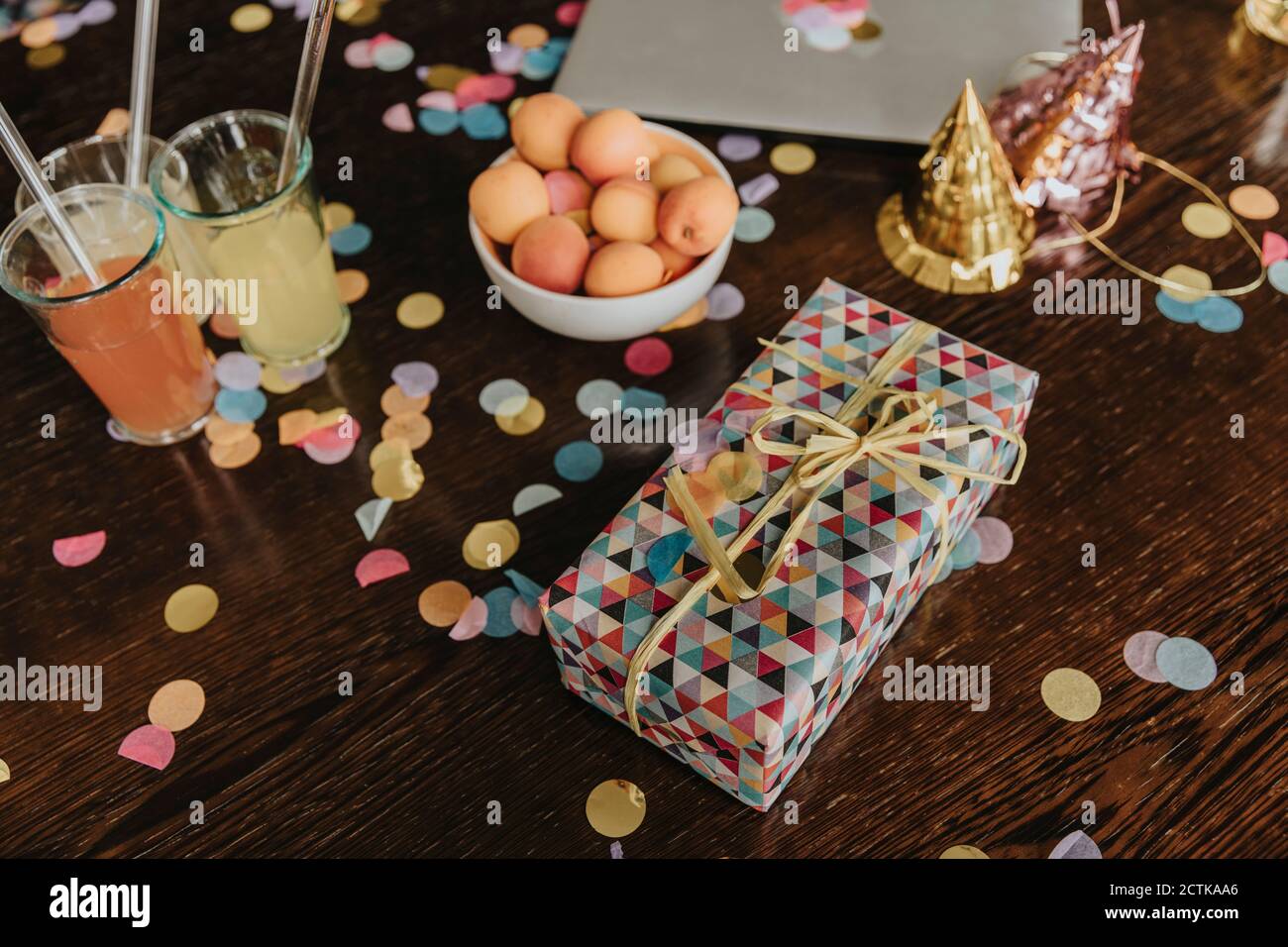 Geburtstagsgeschenk mit Getränken und Aprikosen auf unordentlichen Esstisch Zu Hause Stockfoto