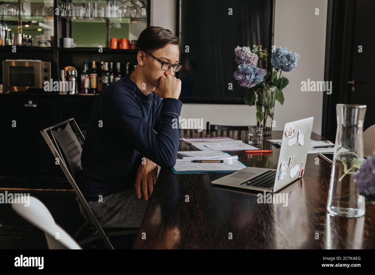 Junger Mann, der von zu Hause aus lernt, mit einem Laptop Stockfoto