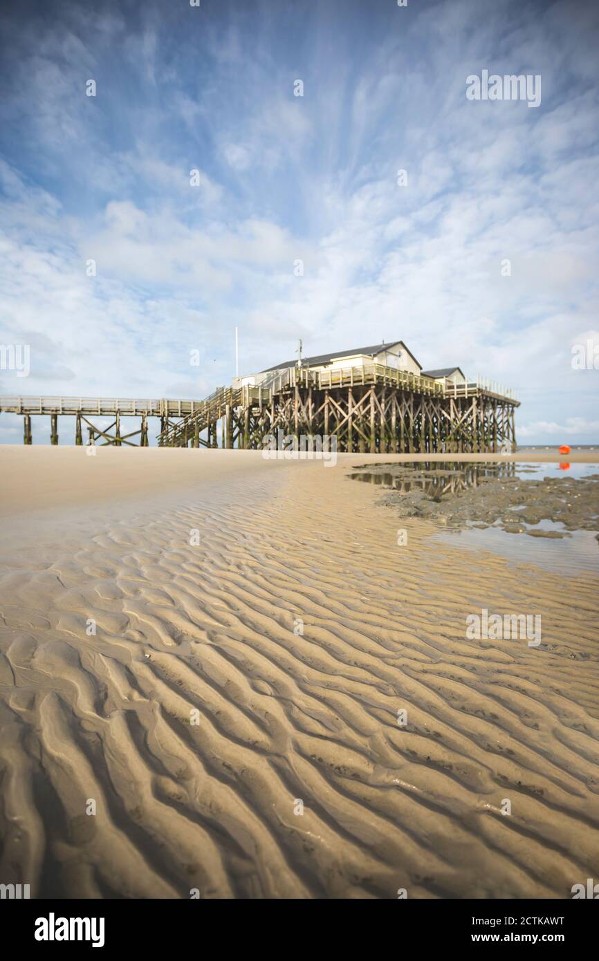 Deutschland, Schleswig-Holstein, Sankt Peter-Ording, gewellter Strandsand mit Pier im Hintergrund Stockfoto