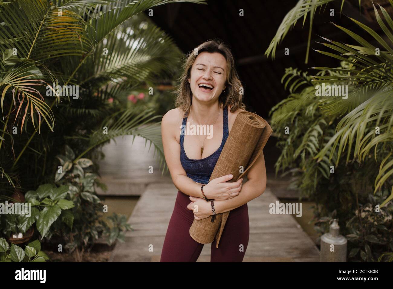Lachende Frau mit Yogamatte Stockfoto