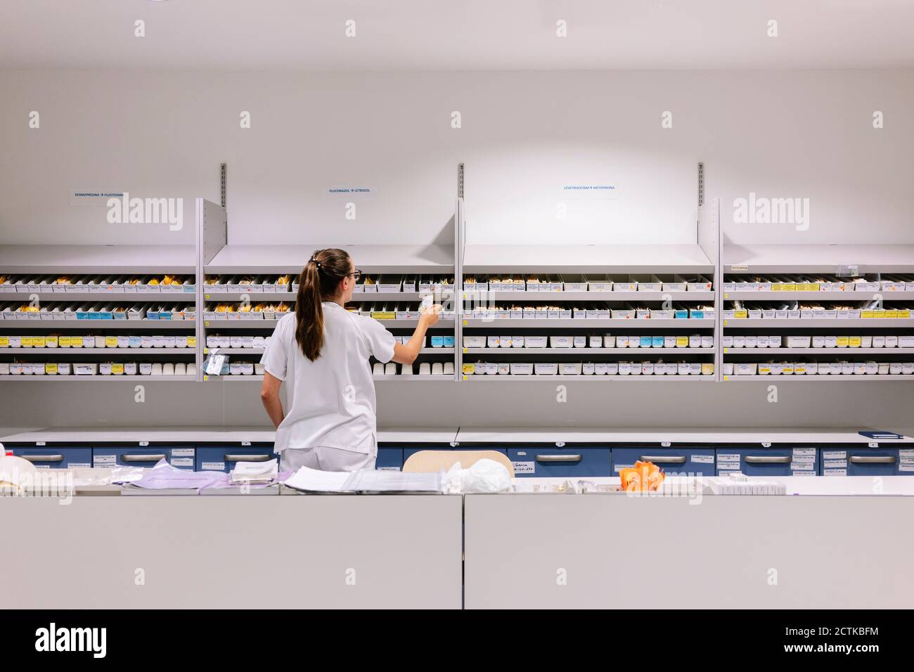 Apothekerin, die Medikamente in den Regalen im Krankenhaus arrangiert Stockfoto