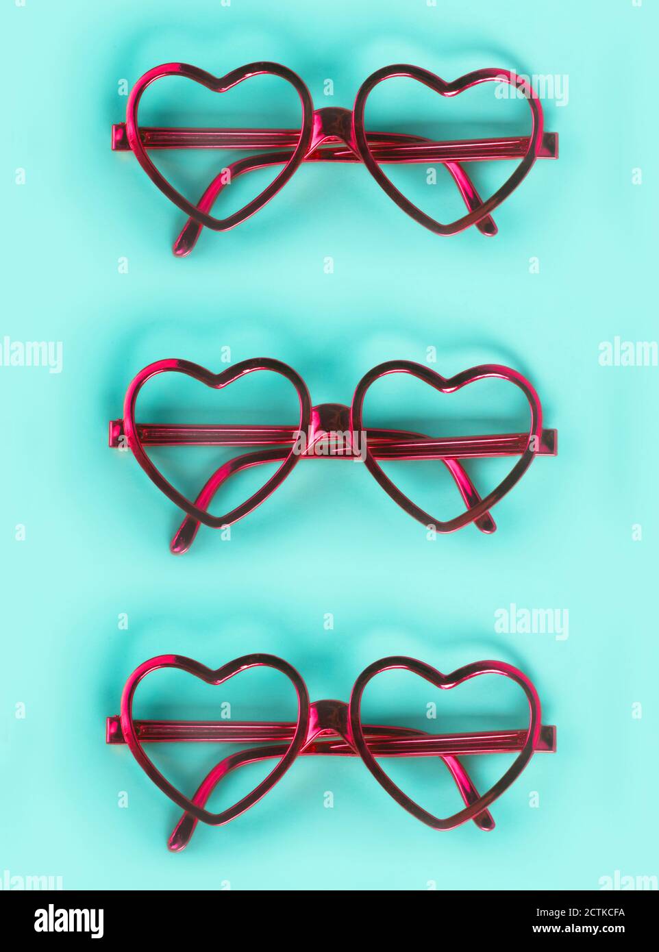 Nahaufnahme von rosa herzförmigen Brillen auf blauem Hintergrund angeordnet Stockfoto