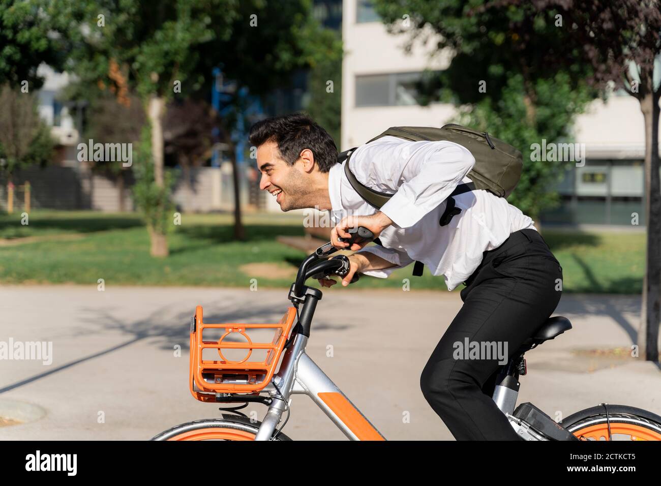 Fröhlicher Geschäftsmann mit Rucksack Reiten Elektro-Fahrrad in der Stadt Stockfoto