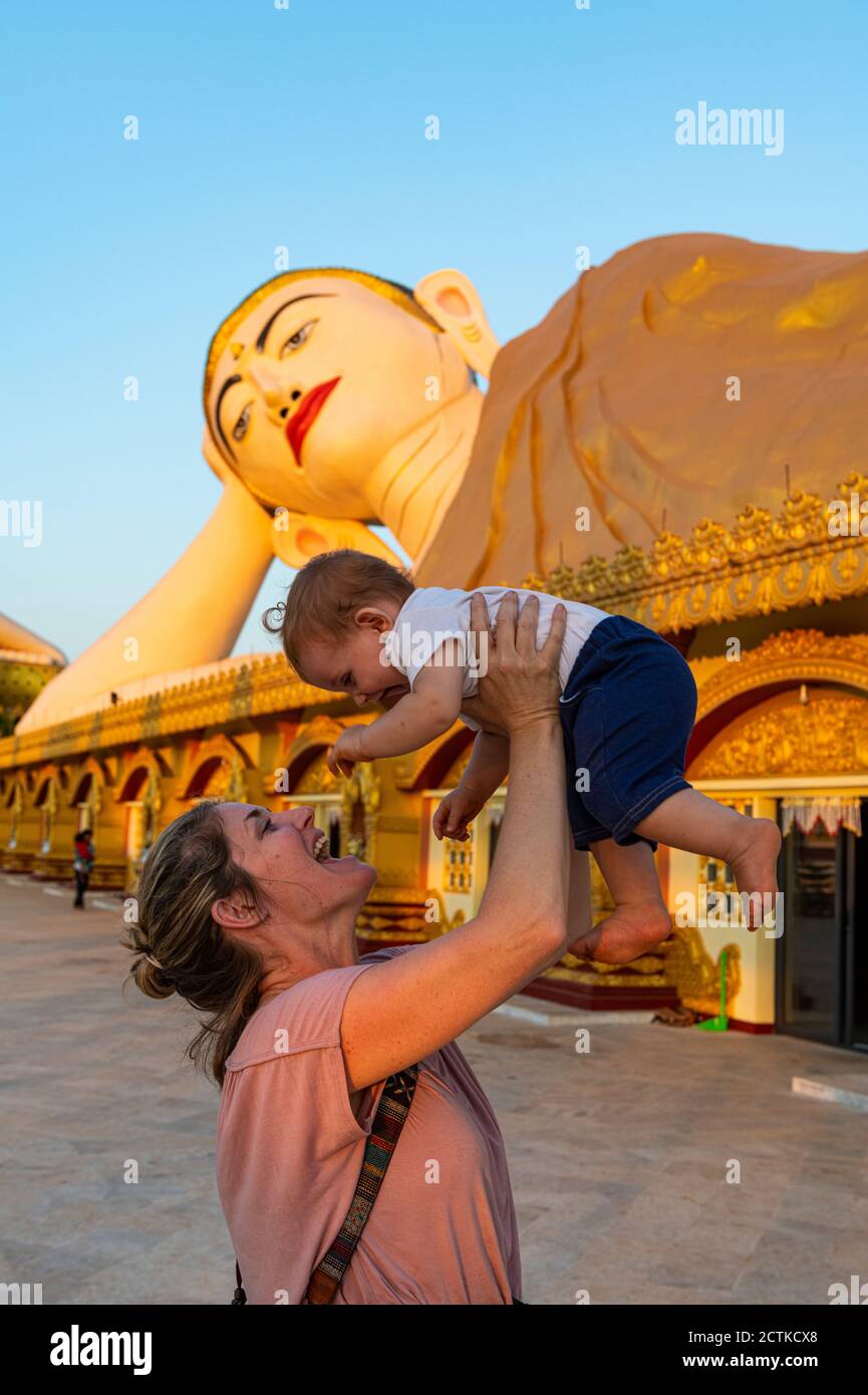 Myanmar, Mon Staat, Mutter hält das Mädchen vor der riesigen Statue des liegenden Buddha im Pupawadoy Kloster Stockfoto