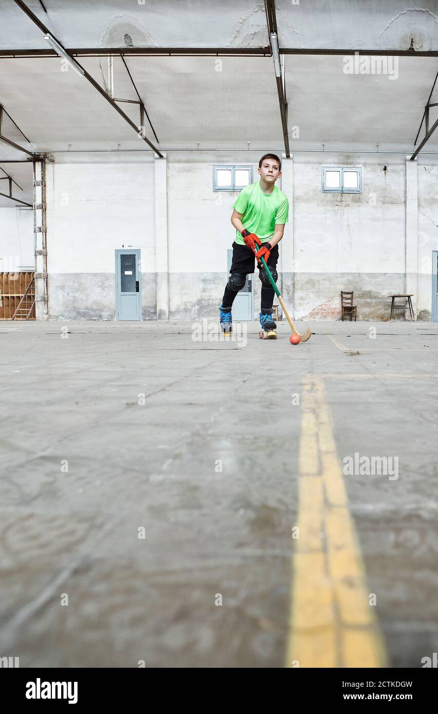 Oberflächenebenansicht des Jungen, der Rollhockey auf dem Platz übt Stockfoto