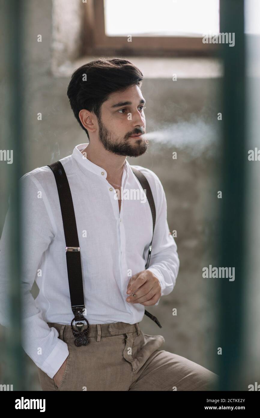 Mann raucht, während er im Zimmer sitzt Stockfoto