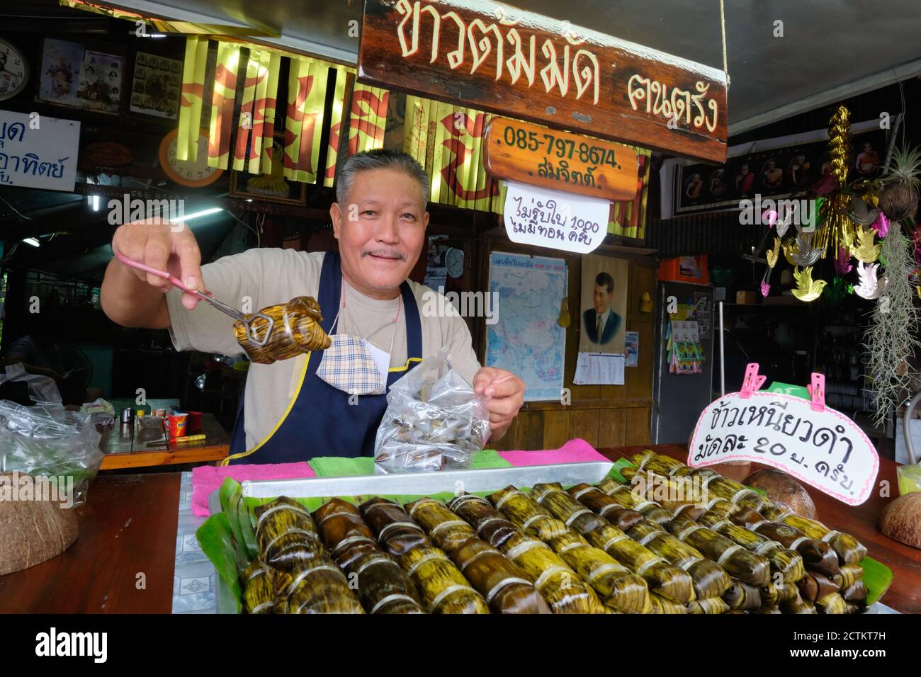 Ein Händler hält Khao Thom Mad (Mat) in Pandanusblatt, einer traditionellen thailändischen Wüste aus klejewem Reis und Bananen gewickelt; Phuket Town, Thailand Stockfoto