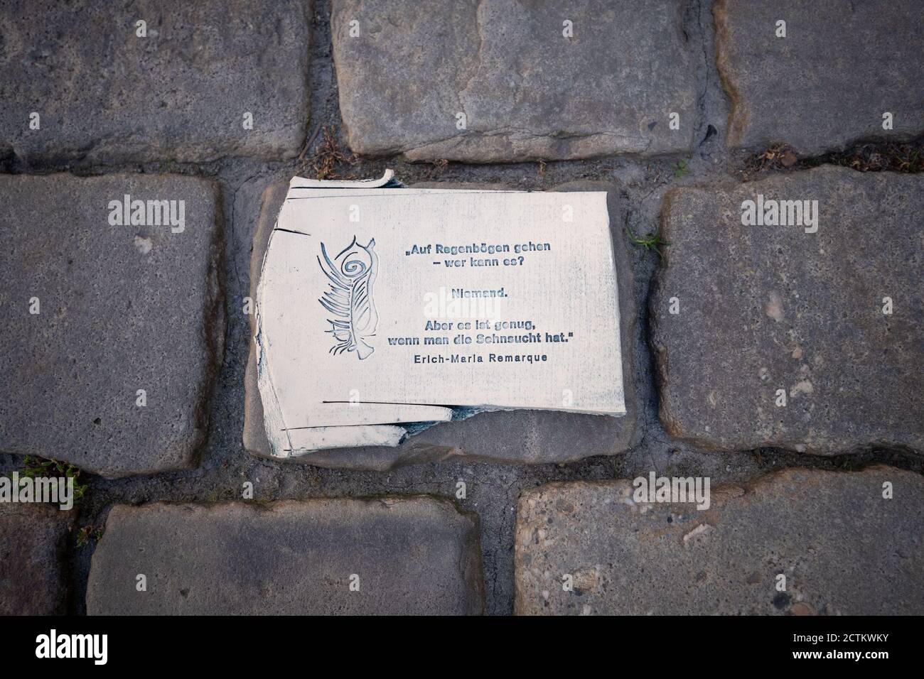 22. September 2020, Niedersachsen, Osnabrück: Auf einem Pflaster liegt ein Keramikscherbe, der mit einem Remarque-Zitat aus dem Roman "der schwarze Obelisk" bedruckt ist. Der Osnabrücker Künstler Volker-Johannes Trieb nutzt die uralte Materialkeramik für soziale Interaktion. Anlässlich des 50. Todestages des Schriftstellers Erich-Maria Remarque am 25. September will Trieb hunderte von Keramikscherben in der Stadt verteilen. Foto: Friso Gentsch/dpa Stockfoto