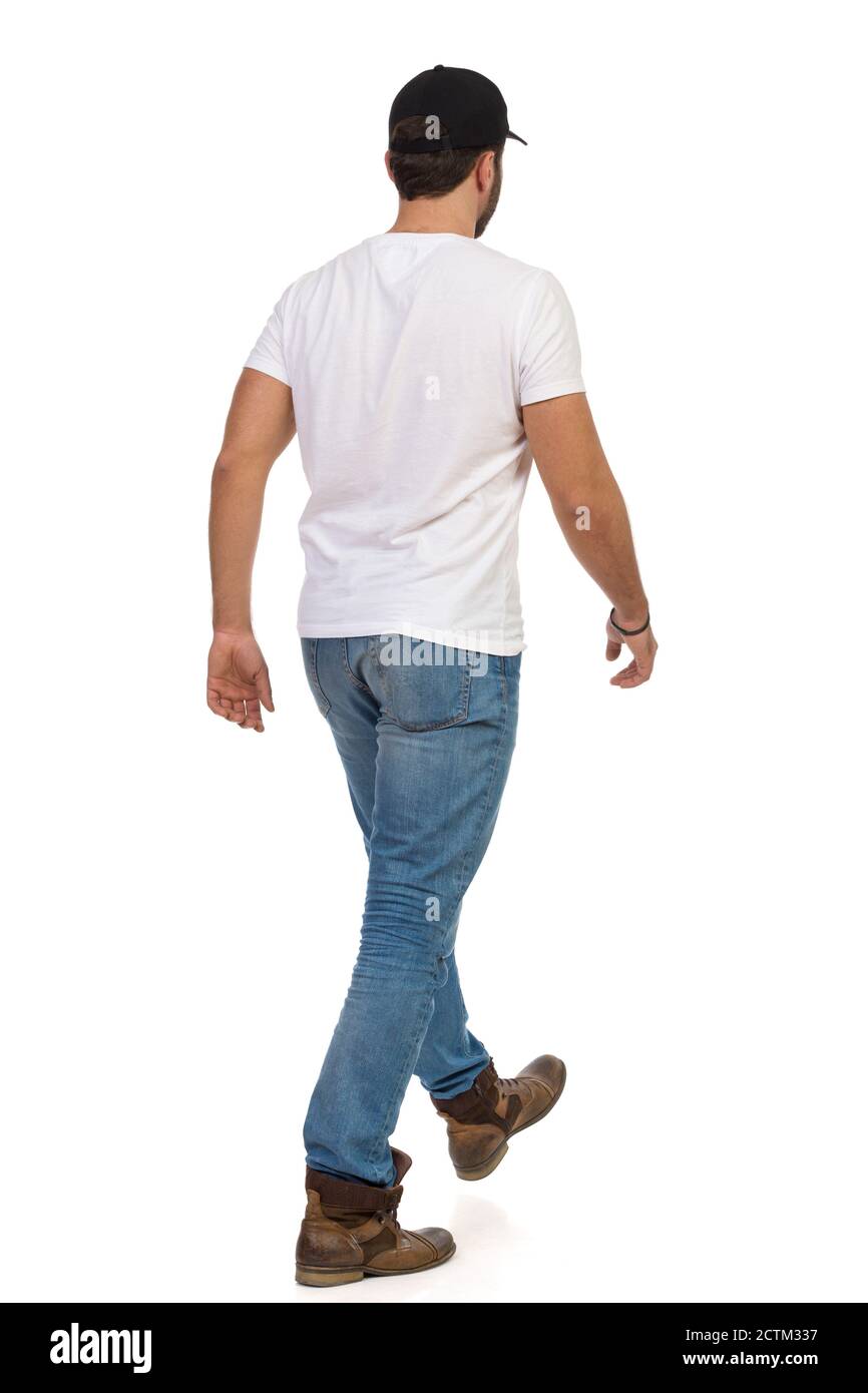 Blick auf den Rücken des Wandermanns, der Stiefel, Jeans, weißes T-Shirt und schwarze Mütze trägt. Studioaufnahme in voller Länge, isoliert auf Weiß. Stockfoto